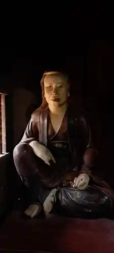 A portrait-like seated figure, lit from the side.